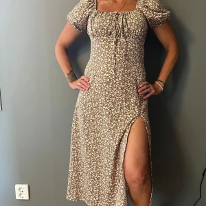 Fin sommarklänning  - Beige blommig klänning i vacker passform med slits. Passar Stl S-M. Knappt använd. 