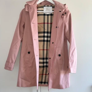 Burrberry trenchcoat - Rosa Burberry trenchcoat med mörkbruna knappar i storlek 14 år/164 cm. Nästan oanvänd och i gott skick!