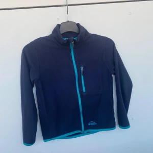 Fleecetröja/jacka  - Marinblå fleecetröja/jacka med dragkedja i märket Mc Kinley. storlek 130, skulle dock säga att den passar bättre som en 120. En bröstficka med dragkedja. Perfekt till kallare sommarkvällar/vår & höst.