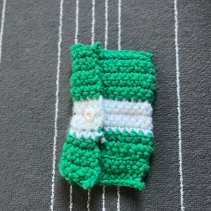 Grön och vit stickad väska - En handgjord virkad väska i grönt och vitt. Väskan har en knappstängning och är perfekt för att förvara småsaker som smink eller pennor. En mini handgjord virkad väska!