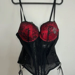Sexig röd svart korsett B85-C34 kupa - Säljer då jag aldrig använt. Den är i gott skick! Storlek S med kupa C34 men kan även passa B85😊