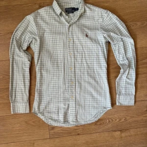 Ralph Lauren Skjorta - Mycket fint skick utan några defekter Storlek S Mått: Total längd 70cm, bredd under armarna 49cm Färg Vit med blåa och gröna ränder i ett rutigt mönster
