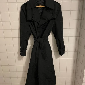 Trenchcoat  - Svart trenchcoat från Juresco i storlek S.