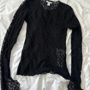 Svart spetsblus från Amisu - En svart topp i spets från Amisu. Tröjan har långa armar och splits längst ner på ärmen. Perfekt för festliga tillfällen. Säljer då den inte kommer till användning💕💕
