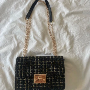Svart handväska  - Svart handväska med guldiga detaljer. Helt oanvänd 