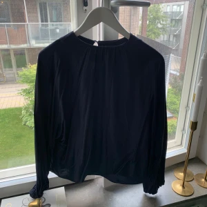 Svart långärmad tröja från Wera - En elegant marinblå långärmad blus från Wera, tillverkad av 100% viskos. Tröjan har en enkel och stilren design med en rund halsringning.