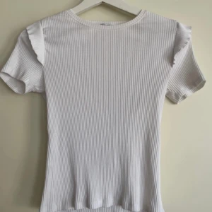 Volang topp - Vit tröja med volanger på axlarna, den är knappt använd och används inte därför säljs den.