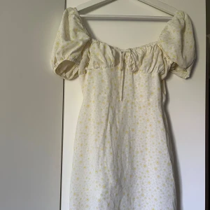 Fin miniklänning från Nelly - Fin sommarklänning från glamorous, vit med gula blommor och puffärmar. Endast använd enstaka gång🤍