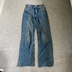 Blå jeans från Perfect Jeans - Säljer ett par snygga blå jeans från Gina Tricot i storlek 34. De är i en klassisk blå färg och har en straight fit men åt det mer wide leg hållet. Jeansen har en knapp och dragkedja framtill samt fem fickor. Perfekta för vardagsbruk och kan matchas med det mesta i garderoben. De är i mycket bra skick och redo för en ny ägare!