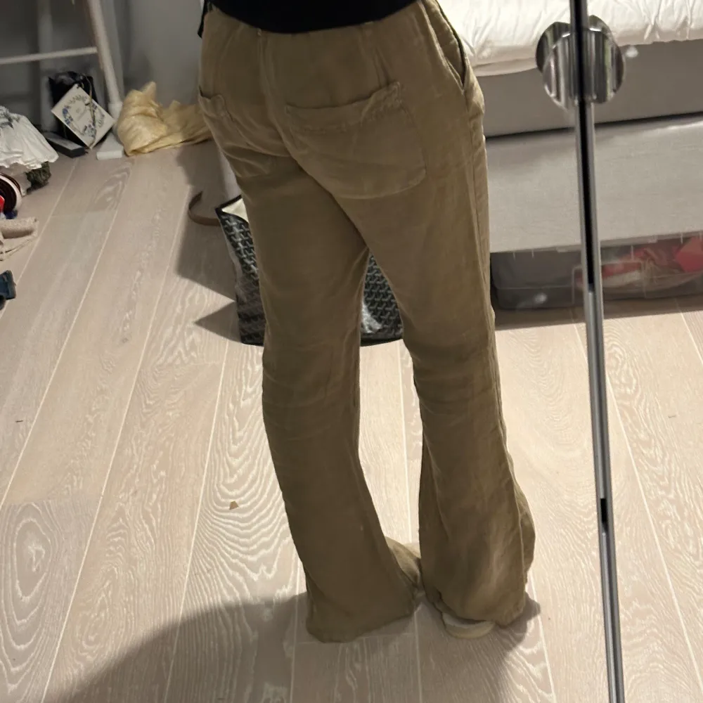 Ett par beige linnebyxor i storlek medium. Byxorna har en låg/medel midja och en bootcut-stil, vilket ger en bekväm och stilren passform. storlek S från zara. Jeans & Byxor.