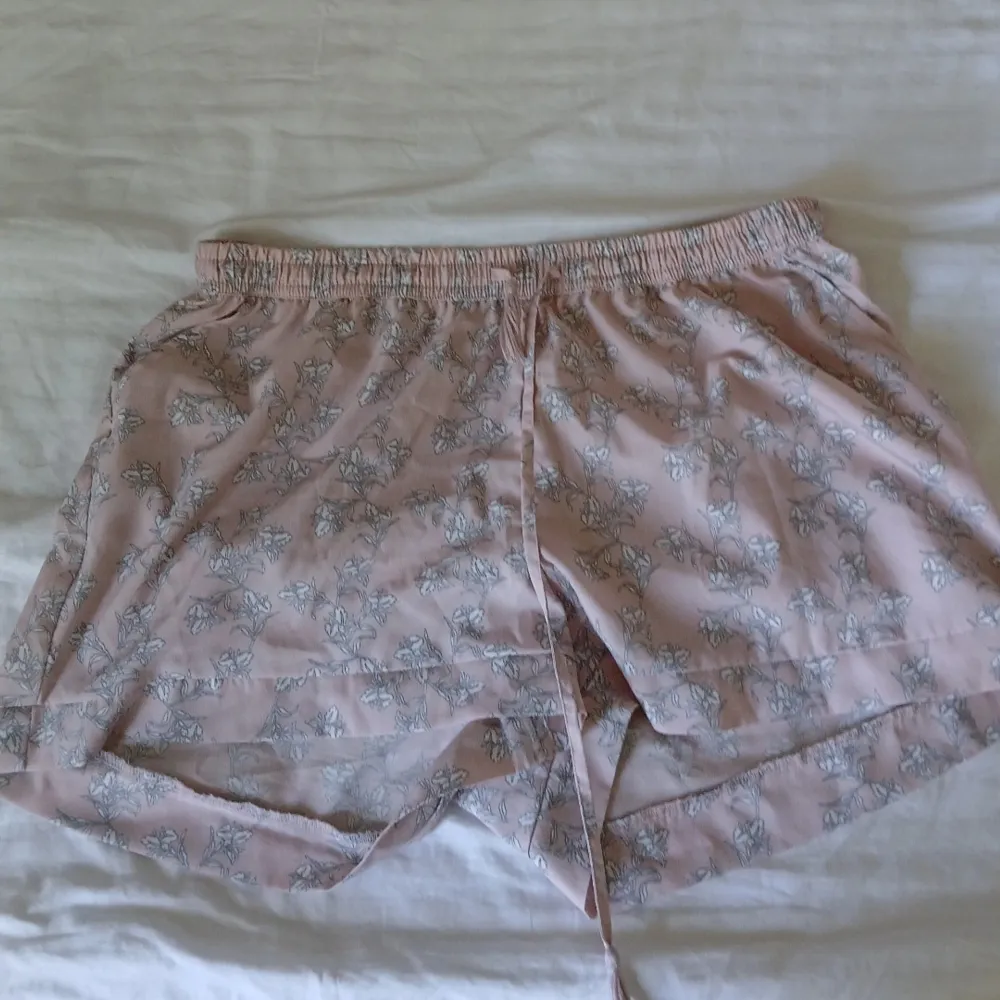 Rosa shorts med vita blommor på. Storlek M men är stretchiga, så passar säkert L också. Säljer då de blivit för stora 💕 1 st för 50 eller alla 3 för 120! . Shorts.