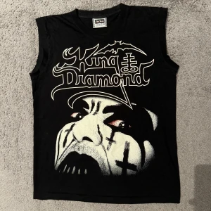 King Diamond Sleeveless T-shirt (Linne) - King Diamond Sleeveless T-Shirt (Linne)! Skick: väldigt bra! Knappt använd. Size Medium Märke: The Roxx Material: 100% Cotton Pris: 159kr Köparen står för eventuell frakt! /KB