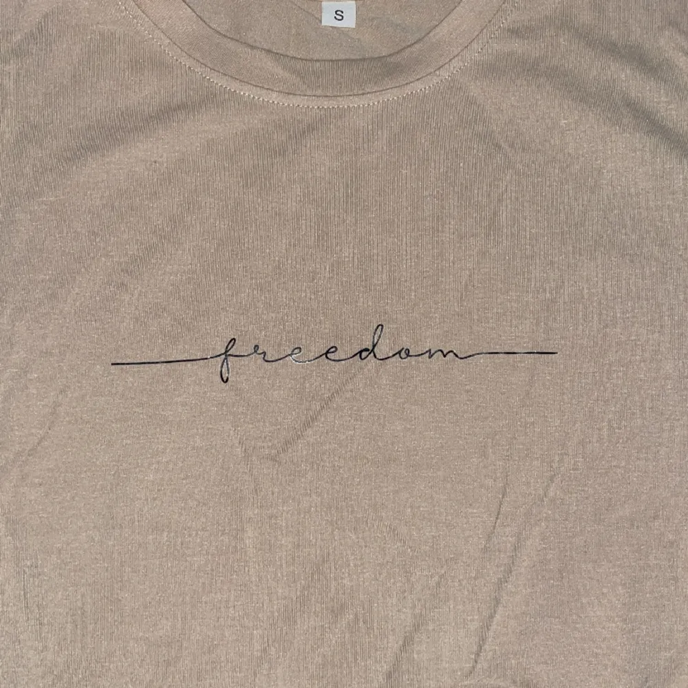 T-shirt i beige med trycket ”Freedom” Oanvänd 1 gång Inget slitage . T-shirts.