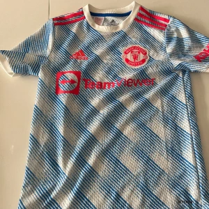 Manchester United tröja  - En ÄKTA vit,blå Manchester United tröja som knappt har används och är i bra skick. Storlekn är 164 barnstolek (13-14 åringar)