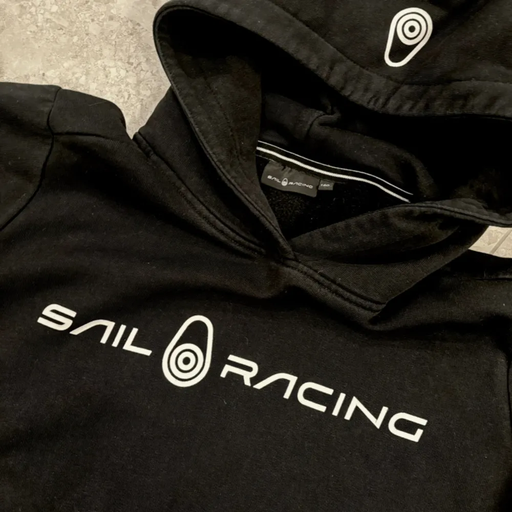 Svart klassisk hoodie från Sail Racing i storlek 160. Fint skick. . Hoodies.