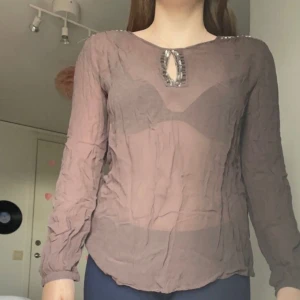 Blus  - En mörkbrun blus med detaljer vid både bröst och axlar storlek L men passar även M (väldigt tunn)
