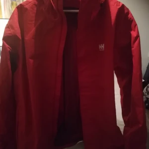 Outdoor Helly Hansen Röd regnjacka, XL - Nästan ny HH Outdoor, tunn, med tunt foder, röd regn och vindjacka. HELLYTECH-material. Använd ett fåtal gånger. Unisex men föredragningsvis för en dam tror jag. 
