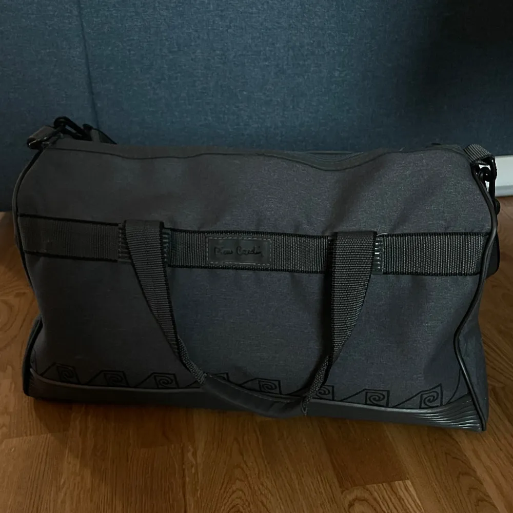 Pierre Cardin weekendbag i bra skick. Små tecken på användning finns, bl.a. saknas tre av fyra knoppar på botten av väskan och utsidan har en lätt synlig fläck på utsidan men den funkar som vanligt och ser snygg ut. . Väskor.