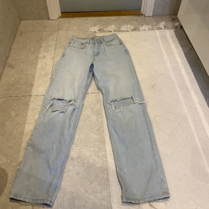 Ett par fina ljusblåa jeans med hål på knäna - Fina ljusblåa jeans från h&m med storlek 32. Är tyvärr för små för mig. Är medelmidjade baggy med hål på knäna. Har använts hyfsat bra men är i bra skick!! Skriv för mer info