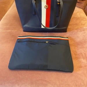 Tommy Hilfiger väska - Aldrig använd. Köpt för 1< år sen. Nypris låg på 2400kr. Tror de ej säljer just denna modell längre. Den mindre väskan ingår och kan väljas att ta bort eller ha kvar i väskan. Pris kan diskuteras vid snabb affär