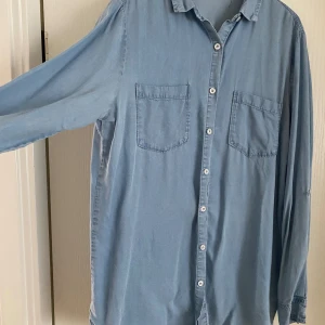 Skjorta/blus från bikbok strl xs  - Skön Vardagsskjorta  Ljusblå  Xs men funkar för s oxå  Knapp för att fästa armslutet 
