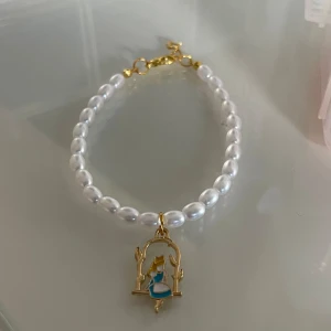 Egen gjort armband  - Egengjort armband från mitt och min lillasysters small business, Alice i underlandet berlock med vita pärlor och guld detaljer 