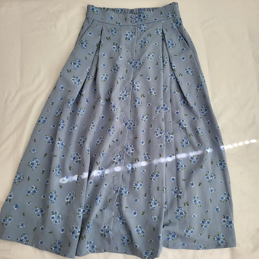 Jättefin oanvänd blå kjol med blommor från Monki, den är jätteskön och har fickor, dock för lång för mig så behöver sälja den💗. Kjolar.