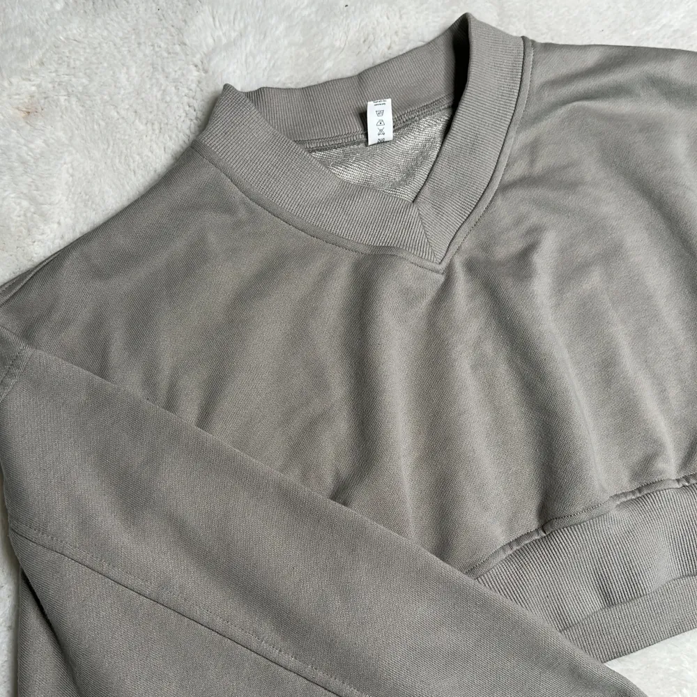 Grå croppad sweatshirt med V-ringning  Oanvänd  Saknar logga, strl: S. Tröjor & Koftor.