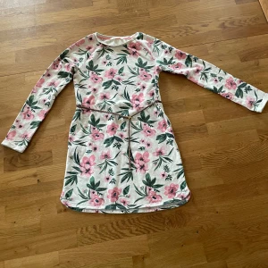 Långärmad klänning med skärp  - Lite tjockare långärmad klänning med blommor och skärp i storlek 158/164