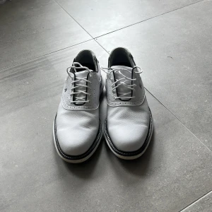 Footjoy Traditions Golfskor - Footjoy Traditions golfskor, Vita med blå sula. använda Max  2 gånger. Helt perfekt skick. Säljer då jag har flera andras par golfskor. Nypris ligger på 1800. Storleken är 41 men skulle säga att den passar 42 utan problem.