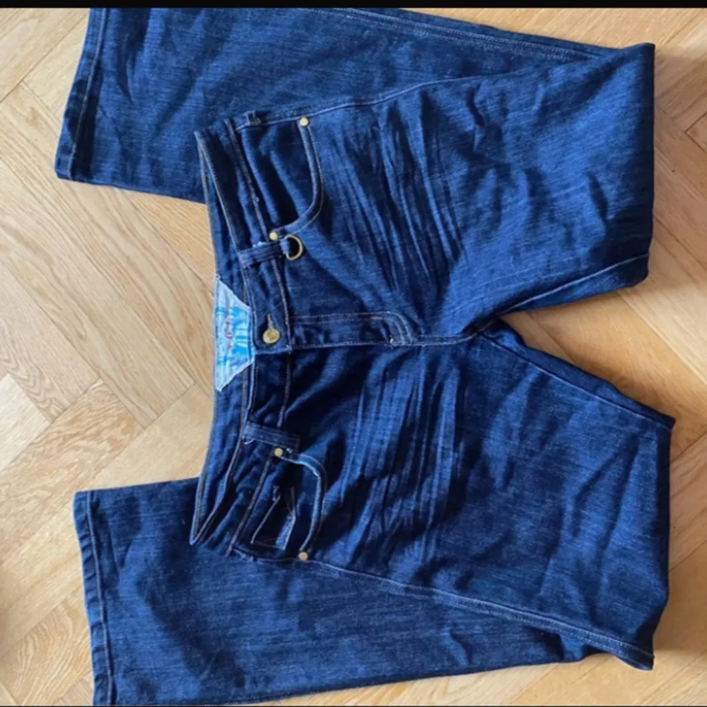 Snygga mörkblå low waist jeans med gulddetaljer och bootcut. Köpta second hand men aldrig använda.. Jeans & Byxor.