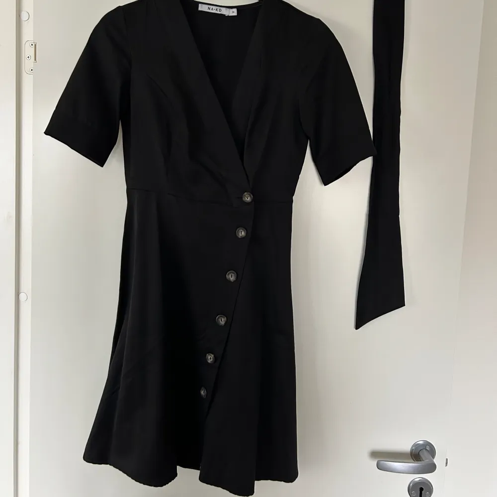 Svart klänning med knappar Storlek: 34 Märke: NA-KD Material: 55% bomull, 45% polyester Skick: Inga anmärkningar. Klänningar.