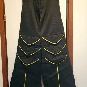 Ravebyxor - Beskrivning: Svarta byxor med neongula detaljer. Märke: Borderline by Lysholt Storlek: 28", Small Skick: Använda någon enstaka gång, mycket gott skick. Material: 55% bomull, 45% cordura  Nakenkatt finns i hemmet