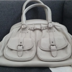 Äkta Dior handbag väska handväska - Säljer min gamla Dior väska i Ivory, från år 2006. Inget större ytslitage bara fått patina. 39 cm bred, generöst med fickor. Höjd 30cm, djup 16cm. Kvitto medföljer om önskas. Mindre smutsfläck på insidan 