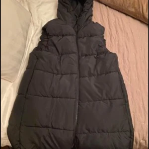 Dunväst  - Lång väst i marinblått. Storlek S. Helt oanvänd. Ev. frakt betalas av köpare. 