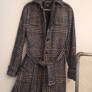 Tommy Hilfiger kappa. - Superfin klassisk kappa i trenchcoat modell.Den är i ull och brunmelerad.I nyskick!