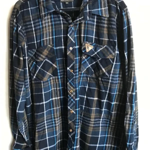 Woodstock skjorta  - Snygg flanellskjorta från Woodstock open air wear. Bäver märke på ena fickan, grön blå rutig med 