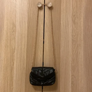 Väska - Snygg svart väska köpt på Ullared! Den har 2 stora innerfack och ett litet med dragkedja. Kedjan är guldfärgad men dock tappa lite färg men inget man direkt märker och en liten skada där framme extremt liten! Skriv för frågor eller fler bilder!😊