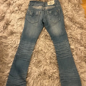 Lågmidjade jeans - Så fina Lågmidjade jeans som tyvärr var försmå för mig. Jätte coola detaljer. Dem är lätt utsvängda. Midjemått 32 cm och innerbenslängd 78 cm