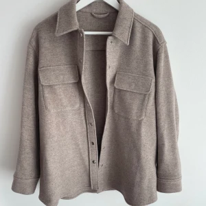 Kort kappa från &other stories - Helt oanvänd kort kappa från &other stories i färgen grå/beige. Säljer då den inte kommit till användning. Den ser tunn ut på bilden men är samma tjocklek som de flesta kappor har💗