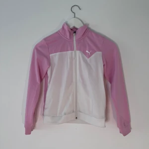 Rosa/vit sport flis från puma storlek 140 unisex - En tunn sport tröja från puma. Storlek 140 och passar både tjej och kille. Andvänd men är i bra skick, har dok en två små fläckar på vänster arm men är inte så synliga. Fråga gärna om bild om ni är osäkra☺️