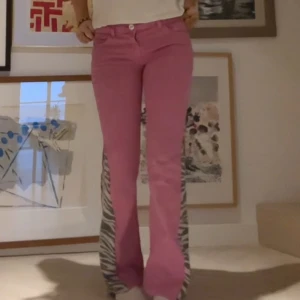Rosa lågamidjade utsvängda jeans med zebramönster på sidorna  - Jättefina utsvängda lågamidjade rosa jeans med zebra mönster på sidorna. Har gjort om själv så dom är unika💗💗