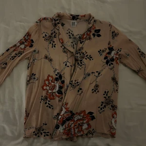 Blommig blus - Välanvänd men fortfarande fin luftig blus från Saint Tropez. Kortare ärmar, med svartglittriga sömmar på krage och ärmar och silvriga knappar. 