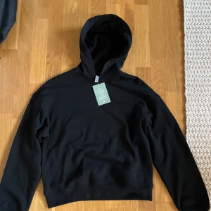 Svart hoodie - Vanlig svart hoodie från Hm. Helt oanvänd med lappen kvar. Säljer pågrund av att den inte passade mig. Nypris 200, mitt pris 150 (Frakt ingår inte i priset)