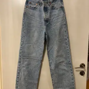 Ljusblåa jeans från Levis i modellen Ribcage Straight. High waisted jeans med knappgylf och bitdekor. Skicket är mycket bra.