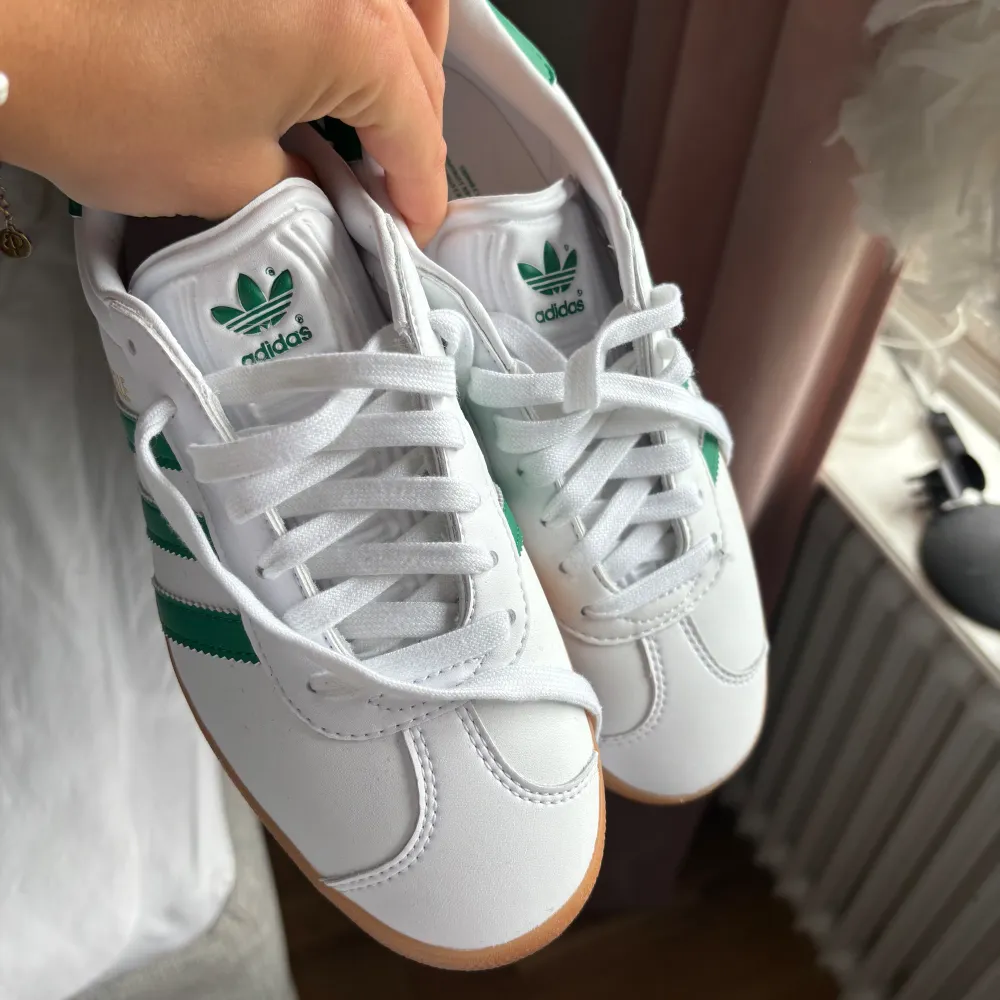 Sprillans nya Gazelle skor från adidas, (aldrig använda) i färgen vit med gröna detaljer. Nypris 1249kr. Skor.