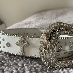 Y2K-bälte - Y2K-bälte med strassstenar och kors. Det är 120cm runt om men det passar mig och jag är en storlek 36/38. Så snyggt och i bra skick men har inte kommit till någon användning så jag säljer det!