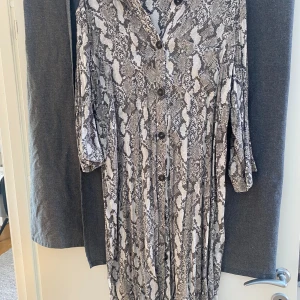 Skjortklänning Snakeprint - Skjortklänning med snake print i ljusgrå/ beige färg. 