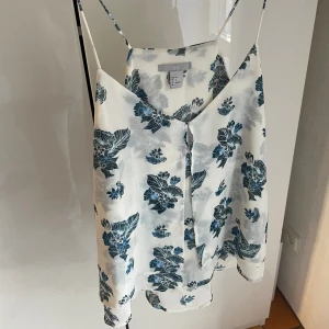 Vitt linne med blommor - Det är kort fram och sedan lite längre där bak, väldigt tunt med fina detaljer på🩷