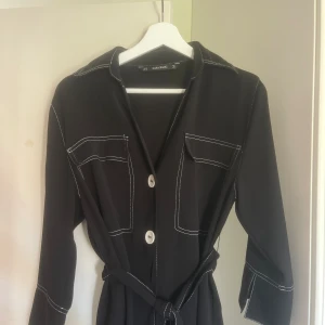 Svart kort klänning med skärp - Snygg långärmad klänning med skärp! Perfekt till vardags samt festligare tillställningar.  Bra skick.